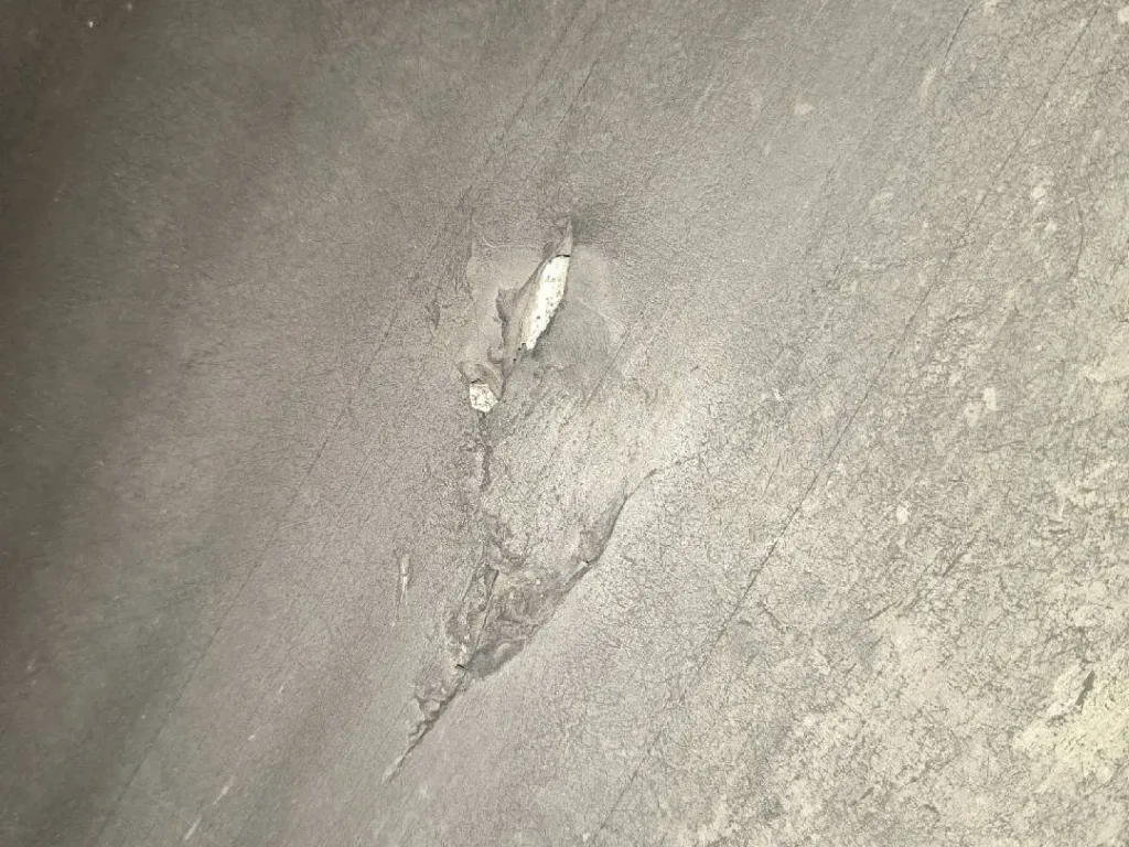 A concentrated puncture or gouge has broken through the cover, showing why local impact damage should be distinguished from general surface wear.